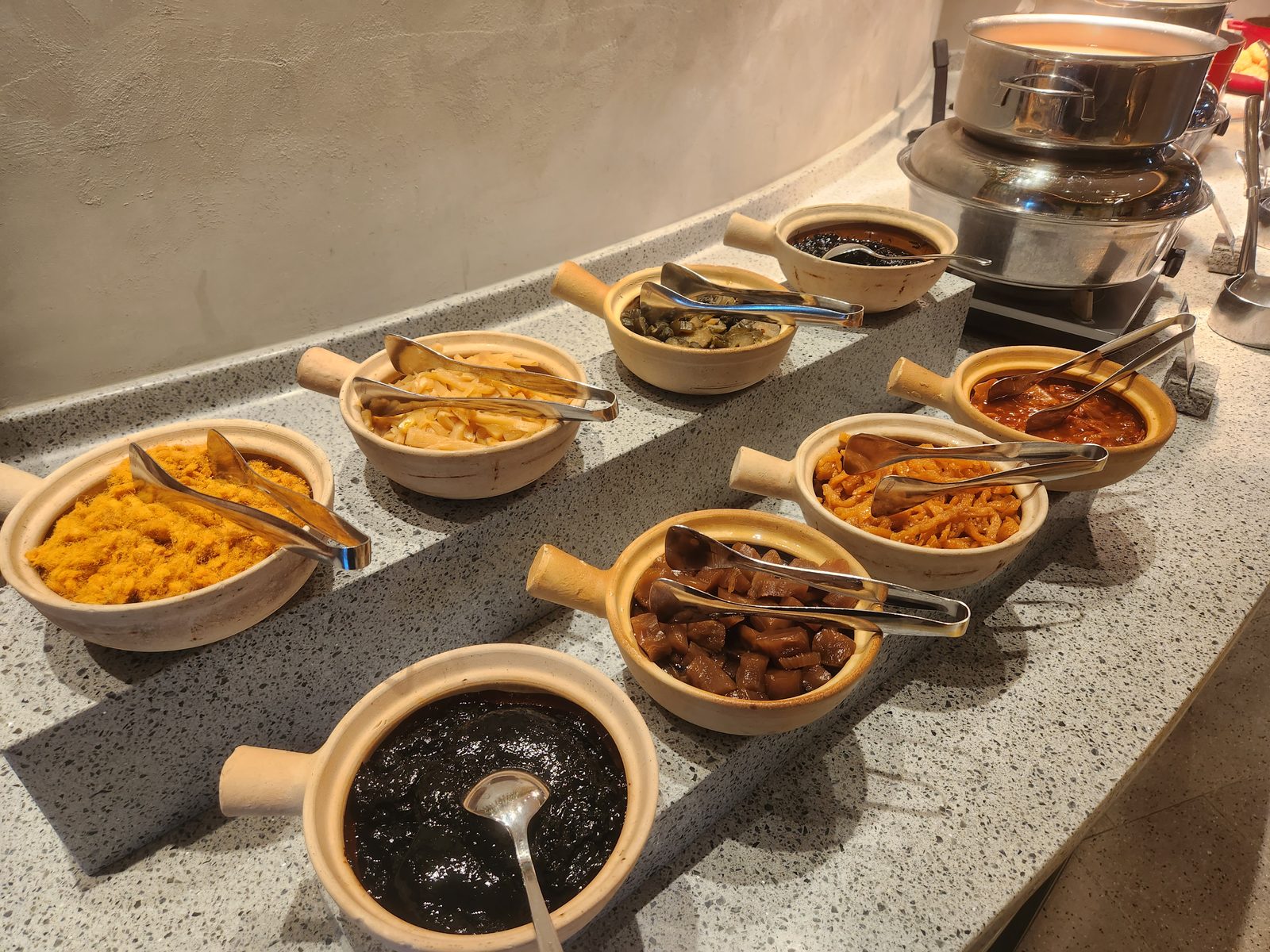 粥品配菜區的陶製小砂鍋,盛著肉鬆、筍絲、酸菜與豆腐乳等配菜