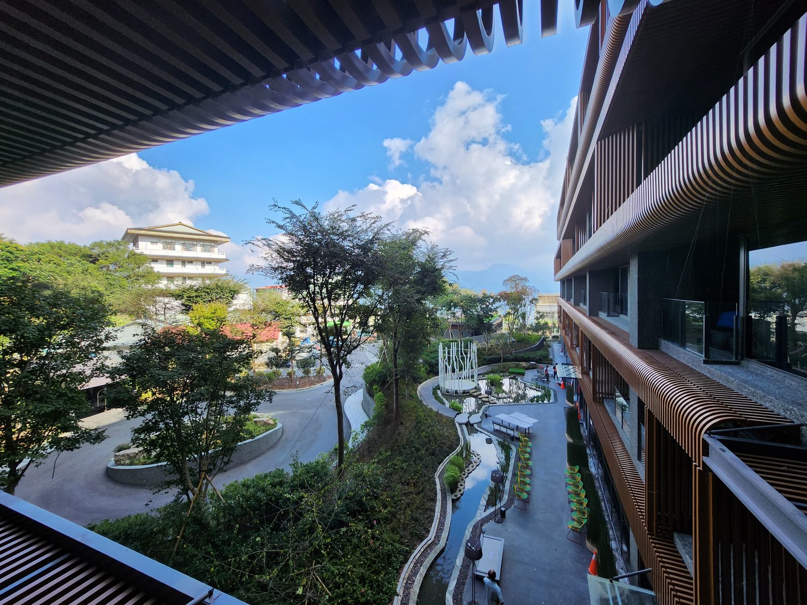 從走廊俯瞰酒店中庭的水景與戶外座椅,遠方是山景