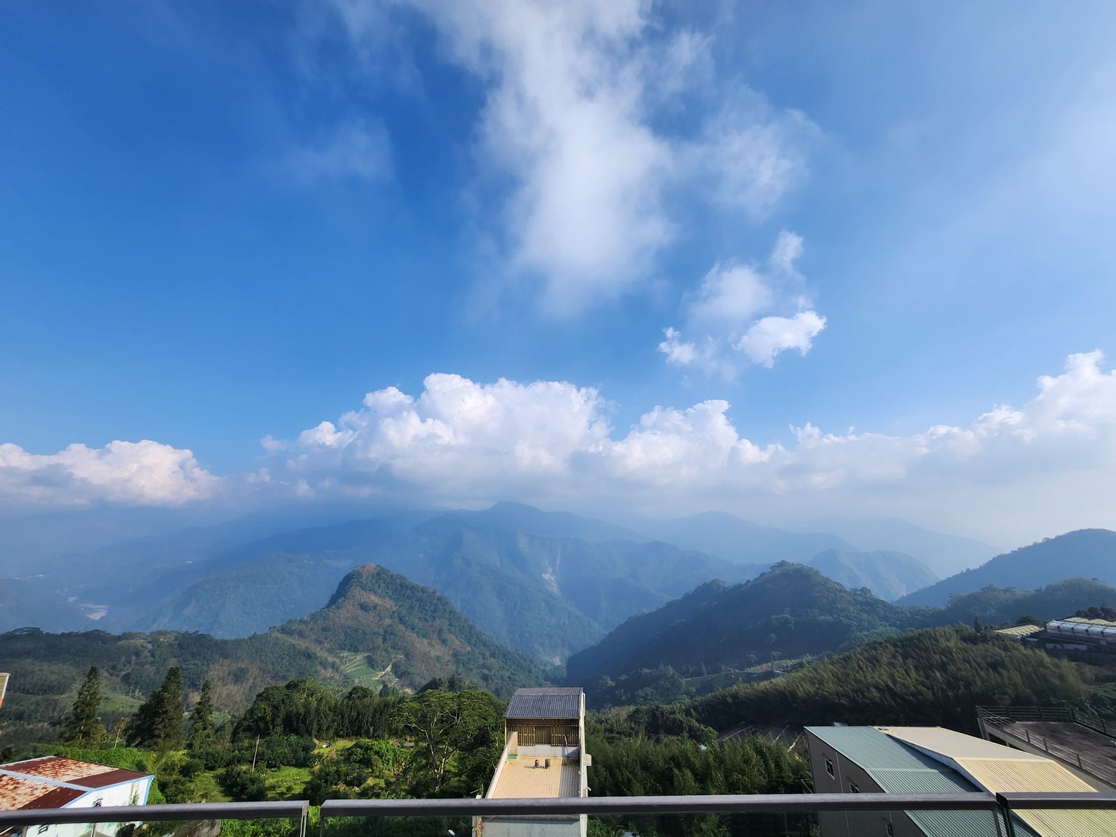 從酒店露台望出去的層層山巒與雲海,前景是山坡上的綠色作物與竹林