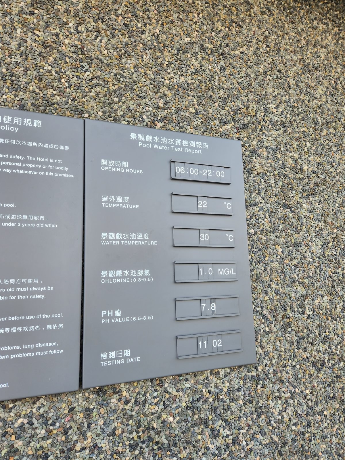 泳池旁的水質檢測公告牌,標示開放時間、水溫與餘氯等數值