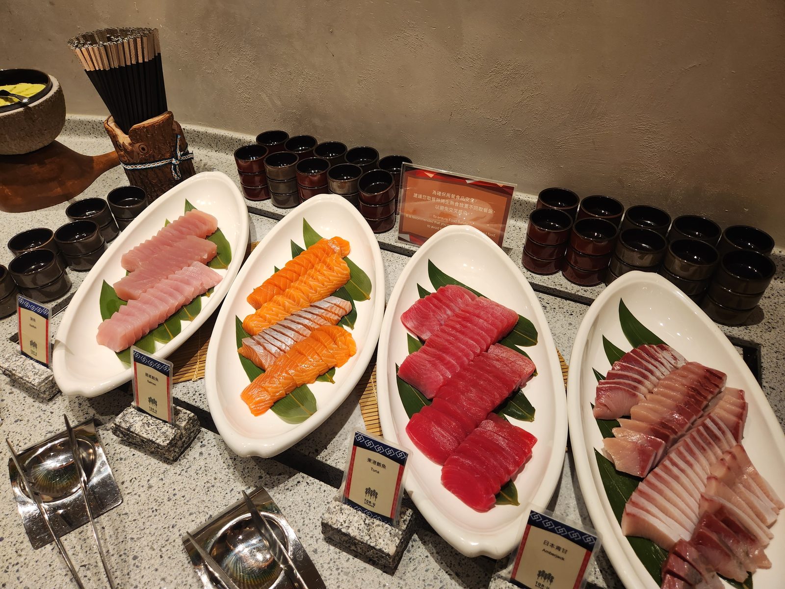 自助餐生魚片區的四盤生魚片與中英對照品名牌